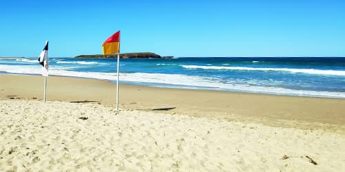 Warilla beach with flags and Windang Island