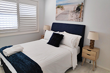 Double bed with plantation shutters on window