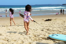 Children on beach running towards surf with boogie board