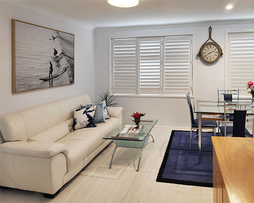 Living room with plantation shutters, large TV, comfortable chairs and coffee table