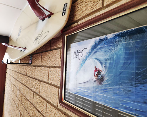 Surfboard and signed surfing picture on wall